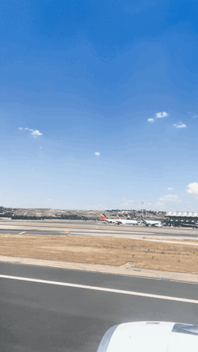 An Airport Runway With Planes Parked On It And A Blue Sky GIF