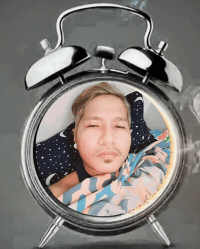 An Alarm Clock With A Man Laying In It GIF