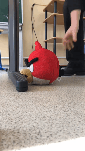 An Angry Bird Stuffed Animal Is Laying On The Floor In A Classroom GIF