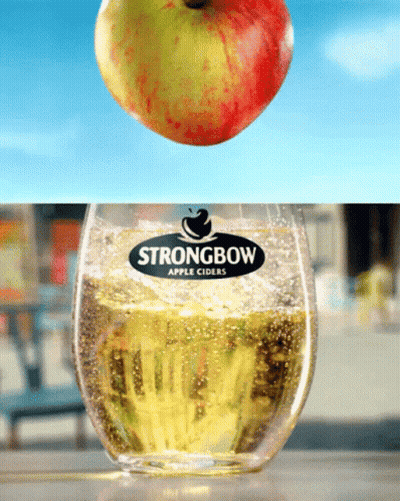 An Apple Is Falling Into A Glass Of Strongbow Apple Cider GIF