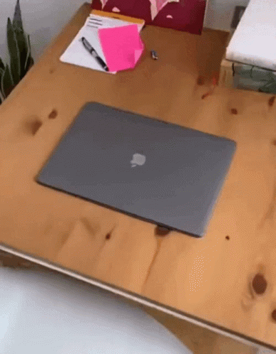 An Apple Laptop Sits On A Wooden Table GIF