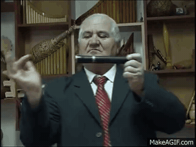 An Elderly Man In A Suit And Tie Is Holding A Pipe In His Hands . GIF