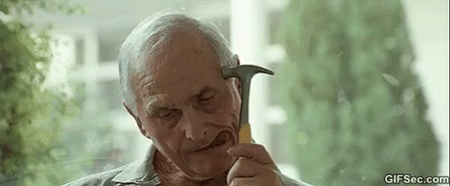 An Elderly Man Is Holding A Hammer In His Hand And Looking At It . GIF
