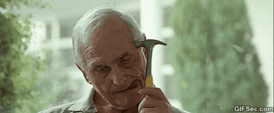 An Elderly Man Is Holding A Hammer In His Mouth And Looking At It . GIF