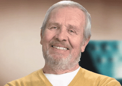 An Elderly Man With A Beard And Yellow Sweater Smiles GIF