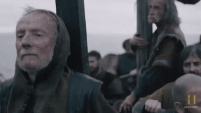 An Elderly Man With A Hood On His Head Is Sitting On A Boat With Other Men . GIF
