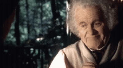 An Elderly Man With Curly Hair Is Smiling While Talking To Another Man In A Dark Room . GIF