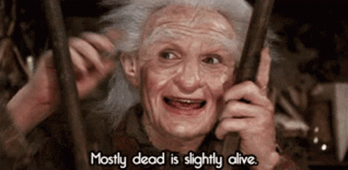 An Elderly Woman Behind Bars With The Words Mostly Dead Is Slightly Alive GIF