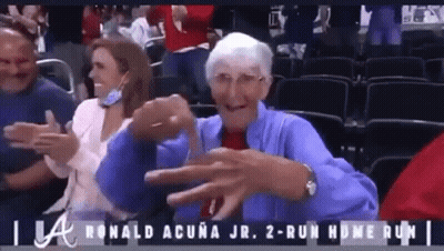 An Elderly Woman In A Blue Jacket Is Sitting In A Stadium Watching A Baseball Game .. GIF