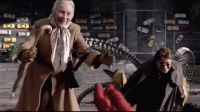 An Elderly Woman In A Scarf Is Standing Next To A Man In A Trench Coat GIF