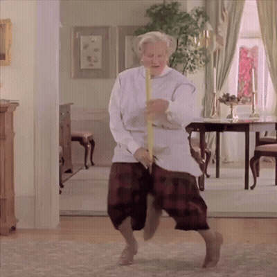 An Elderly Woman Is Dancing In A Living Room With A Yellow Stick GIF