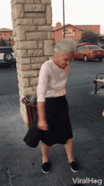 An Elderly Woman Is Dancing In Front Of A Brick Wall And A Sign That Says Viral Hog GIF