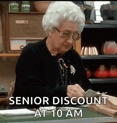 An Elderly Woman Is Sitting At A Desk Counting Money With The Words `` Senior Discount At 10 Am '' Above Her . GIF
