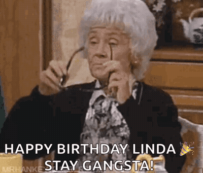 An Elderly Woman Is Sitting At A Table Holding Glasses And Saying Happy Birthday Linda Stay Gangsta ! GIF