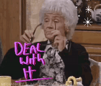 An Elderly Woman Is Sitting At A Table With A Sign That Says Deal With It On It GIF