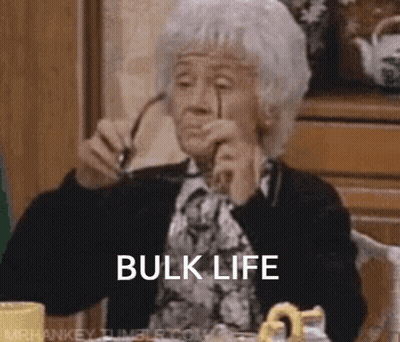 An Elderly Woman Is Sitting At A Table With Glasses In Her Hand And The Words Bulk Life Written On Her Face . GIF