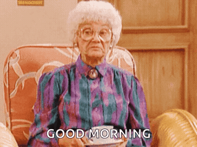 An Elderly Woman Is Sitting In A Chair Holding A Cup Of Coffee And Saying " Good Morning " GIF