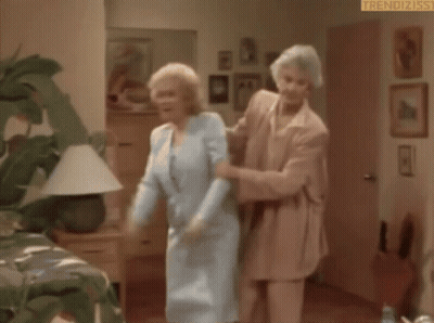An Elderly Woman Is Standing In A Room Holding A Door Open . GIF