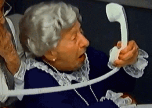 An Elderly Woman Is Talking On A Telephone While Wearing Pearls GIF