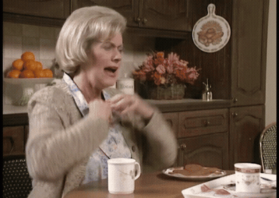 An Elderly Woman Sitting At A Table With A Cup Of Coffee GIF