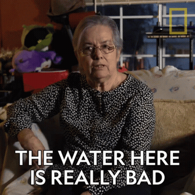 An Elderly Woman Sitting On A Couch With The Words " The Water Here Is Really Bad " GIF