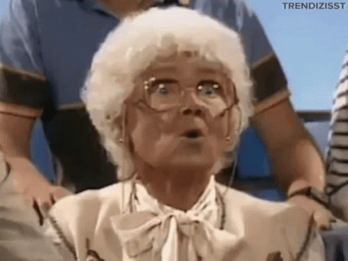 An Elderly Woman Wearing Glasses And A Bow Tie Is Making A Surprised Face . GIF