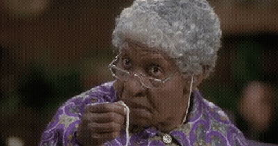 An Elderly Woman Wearing Glasses And A Wig Is Holding A Piece Of String In Her Hand . GIF