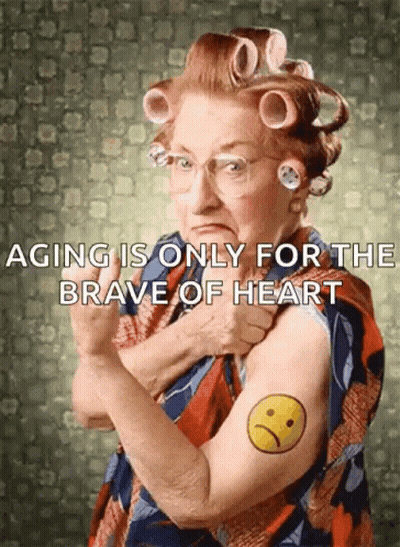 An Elderly Woman With Curlers On Her Hair Has A Tattoo Of An Angry Face On Her Arm GIF