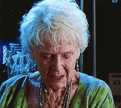 An Elderly Woman With White Hair Is Wearing A Green Sweater GIF