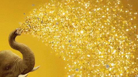 An Elephant 'S Trunk Is Blowing Gold Confetti On A Yellow Background GIF