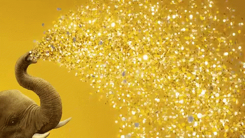 An Elephant 'S Trunk Is Spraying Gold Confetti On A Yellow Background GIF
