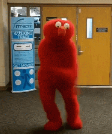 An Elmo Mascot Is Dancing In Front Of A Fitness Walking Track Sign GIF