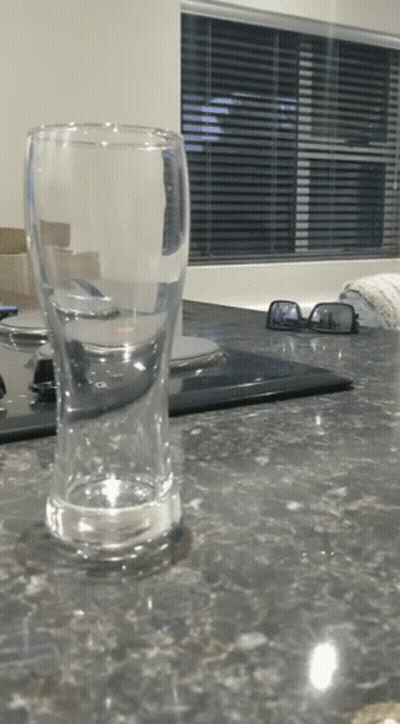 An Empty Glass Sits On A Kitchen Counter Next To A Pair Of Sunglasses GIF