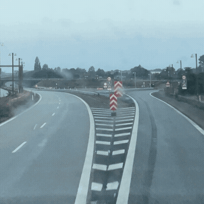 An Empty Highway With A Red And White Chevron Sign In The Middle GIF