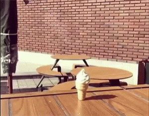An Ice Cream Cone Is Sitting On A Wooden Table GIF