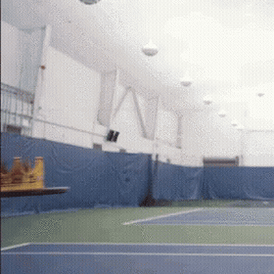 An Indoor Tennis Court With A Table In The Foreground And The Word Ny On The Wall GIF