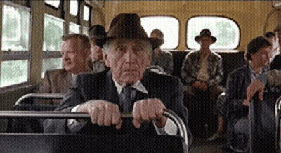 An Older Man In A Hat Is Sitting On A Bus With Other People GIF