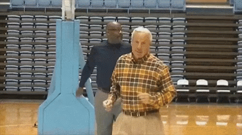 An Older Man In A Plaid Shirt Is Dancing On A Basketball Court GIF