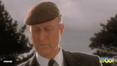 An Older Man In A Suit And Tie Is Wearing A Hat And Looking Down . GIF