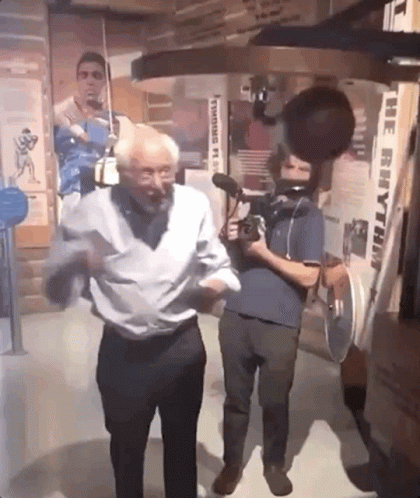 An Older Man Is Dancing In Front Of A Machine That Says The Rhythm GIF