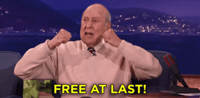 An Older Man Is Sitting At A Desk With The Words Free At Last Written On The Screen GIF