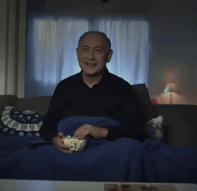 An Older Man Is Sitting On A Couch Eating Popcorn GIF