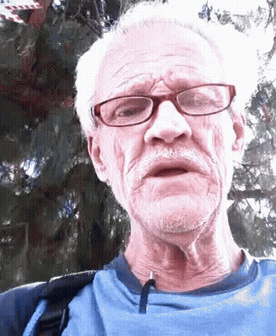 An Older Man Wearing Glasses And A Blue Shirt Is Making A Funny Face GIF