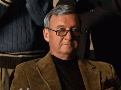 An Older Man Wearing Glasses And A Brown Jacket GIF