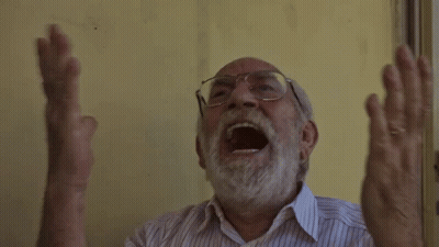 An Older Man With Glasses And A Beard Is Screaming With His Mouth Open GIF