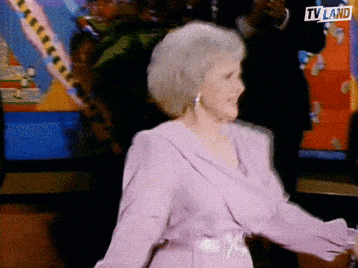 An Older Woman In A Purple Dress Is Dancing In Front Of A Tv Screen That Says Tv Land GIF