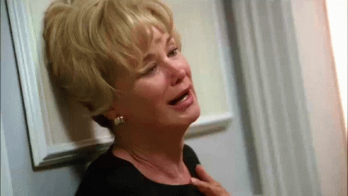 An Older Woman Is Crying While Leaning Against A Door . GIF