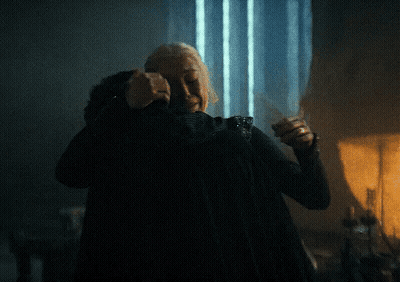 An Older Woman Is Hugging A Younger Woman In A Dark Room GIF