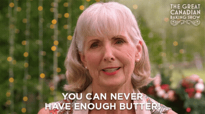 An Older Woman Says " You Can Never Have Enough Butter " In Front Of A Sign For The Great Canadian Baking Show GIF