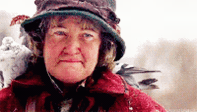 An Older Woman Wearing A Hat And A Red Coat GIF